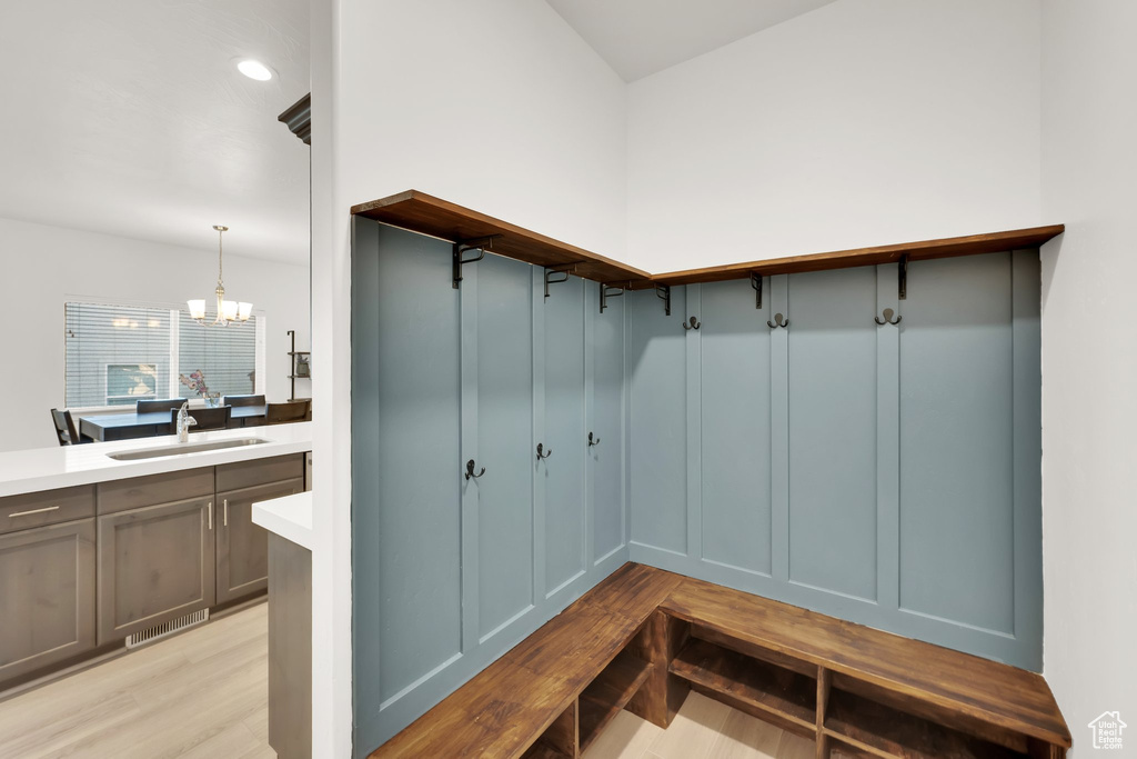 Mudroom with a sink, a chandelier, and light wood-style flooring