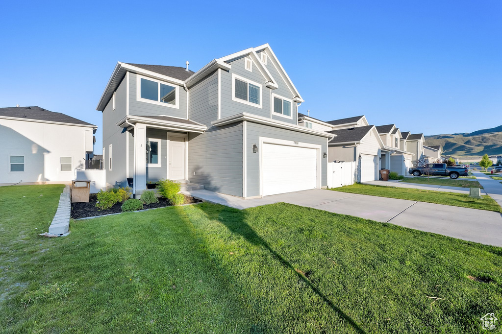 View of front of house with an attached garage, driveway, and a front yard