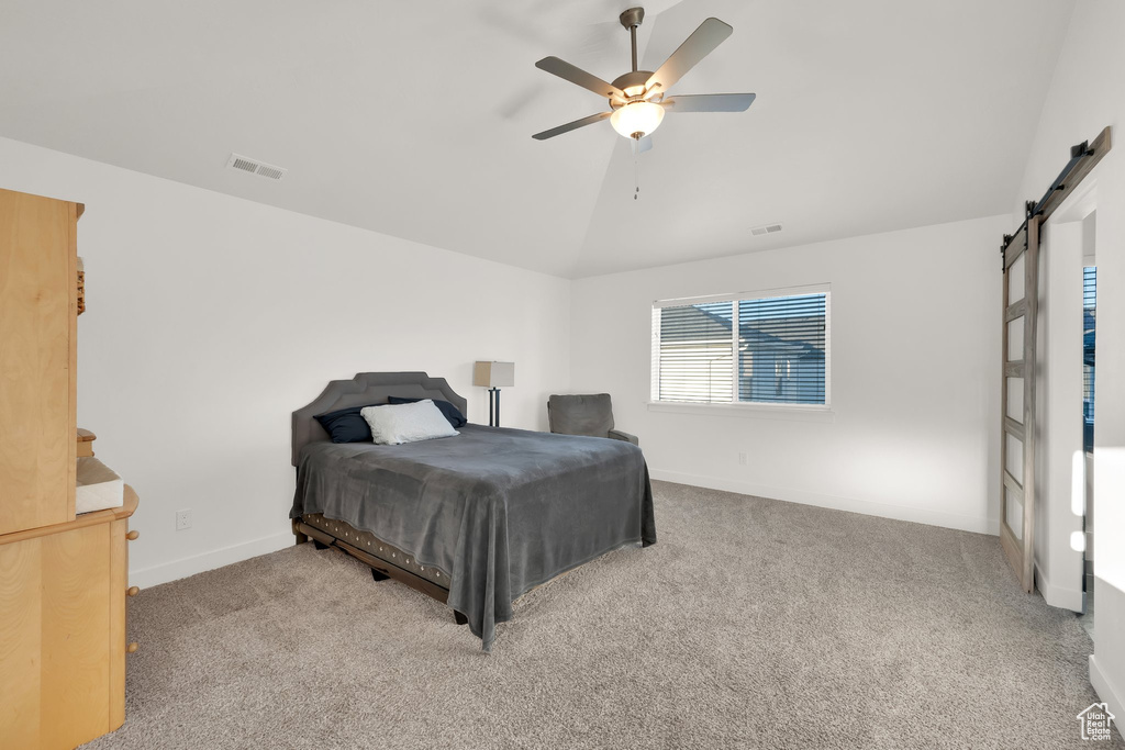 Bedroom with a barn door, vaulted ceiling, carpet flooring, baseboards, and ceiling fan