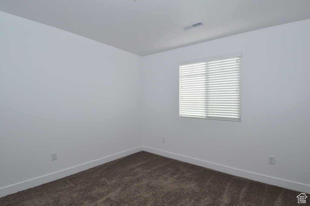 Empty room with dark carpet and baseboards