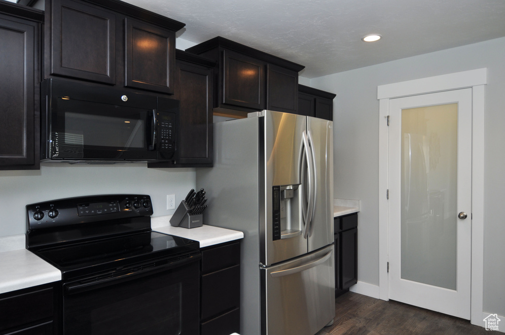 Kitchen with black appliances, light countertops, dark wood-type flooring, and recessed lighting