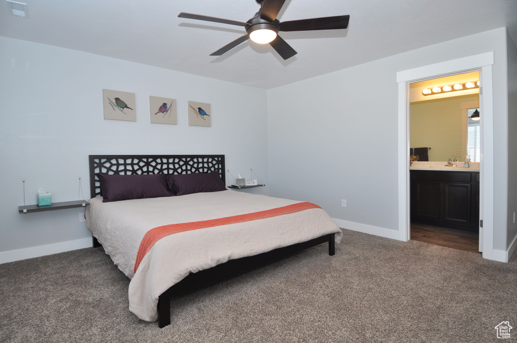 Carpeted bedroom featuring baseboards, ensuite bathroom, and a ceiling fan