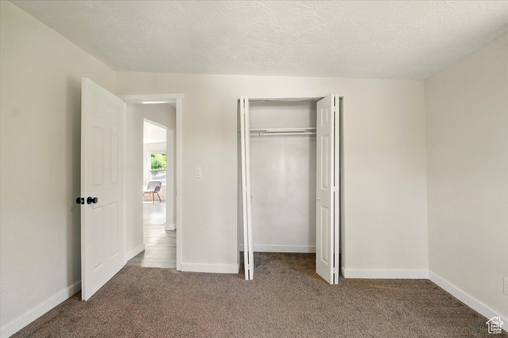 Unfurnished bedroom with carpet, a closet, and baseboards