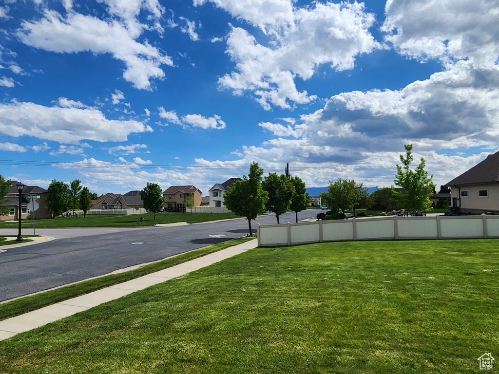 View of asphalt road featuring a residential view and sidewalks