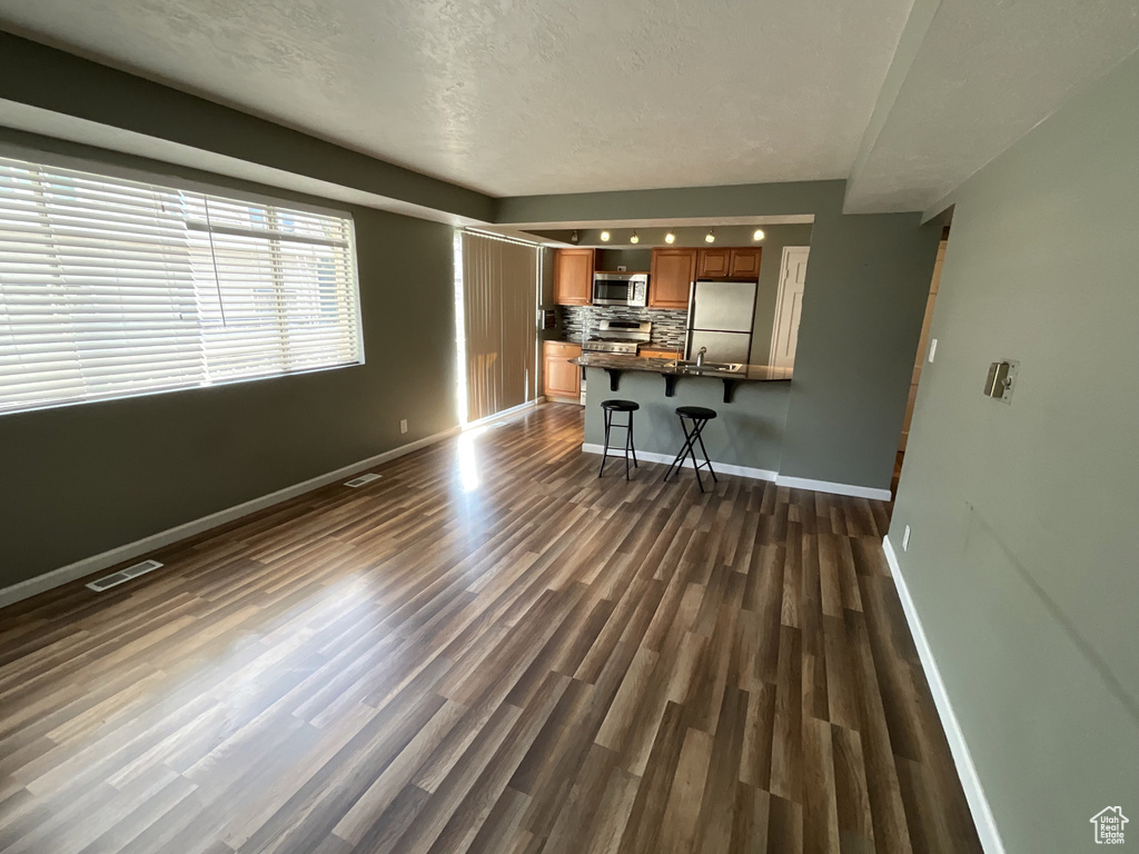 Unfurnished living room with dark wood-style flooring and baseboards
