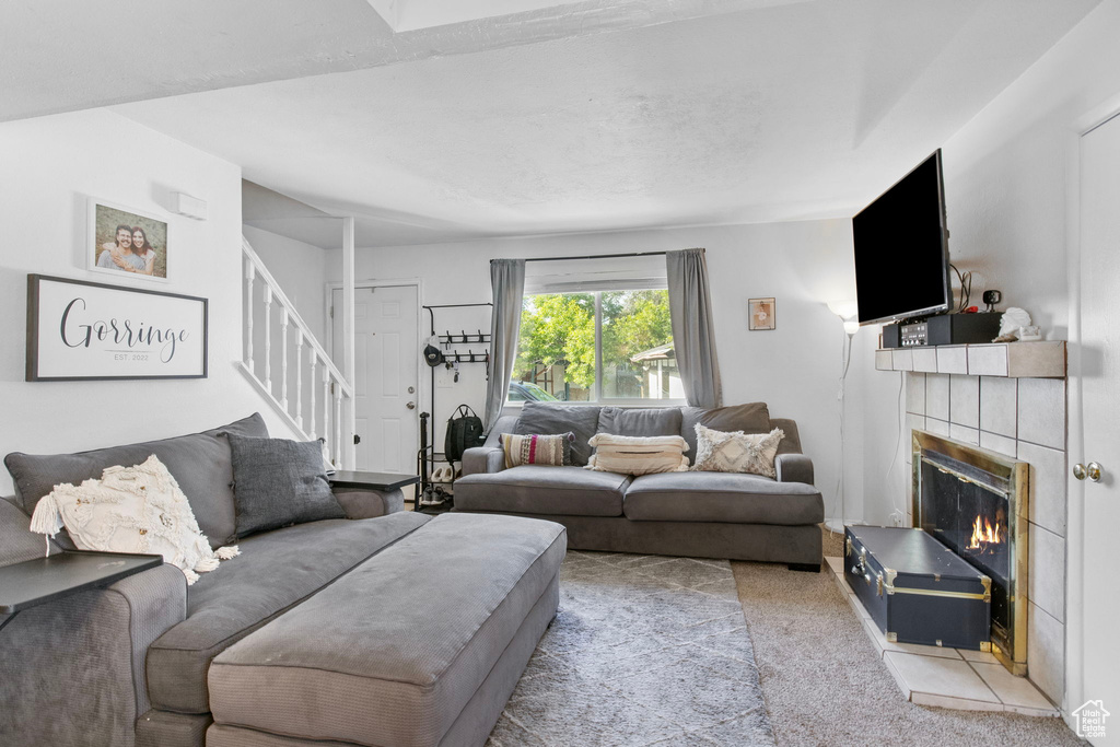 Carpeted living area with stairway and a tile fireplace