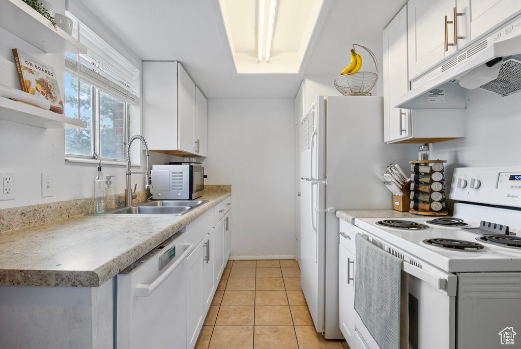 Kitchen featuring white appliances, under cabinet range hood, a sink, and white cabinetry