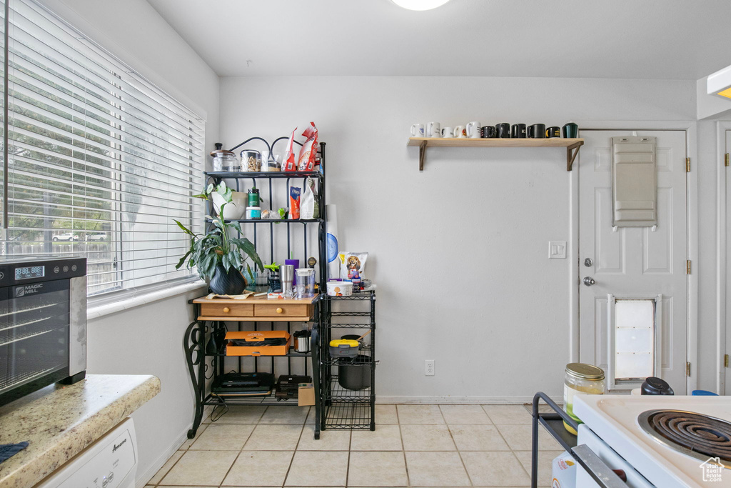 Kitchen featuring light countertops, light tile patterned floors, open shelves, and baseboards