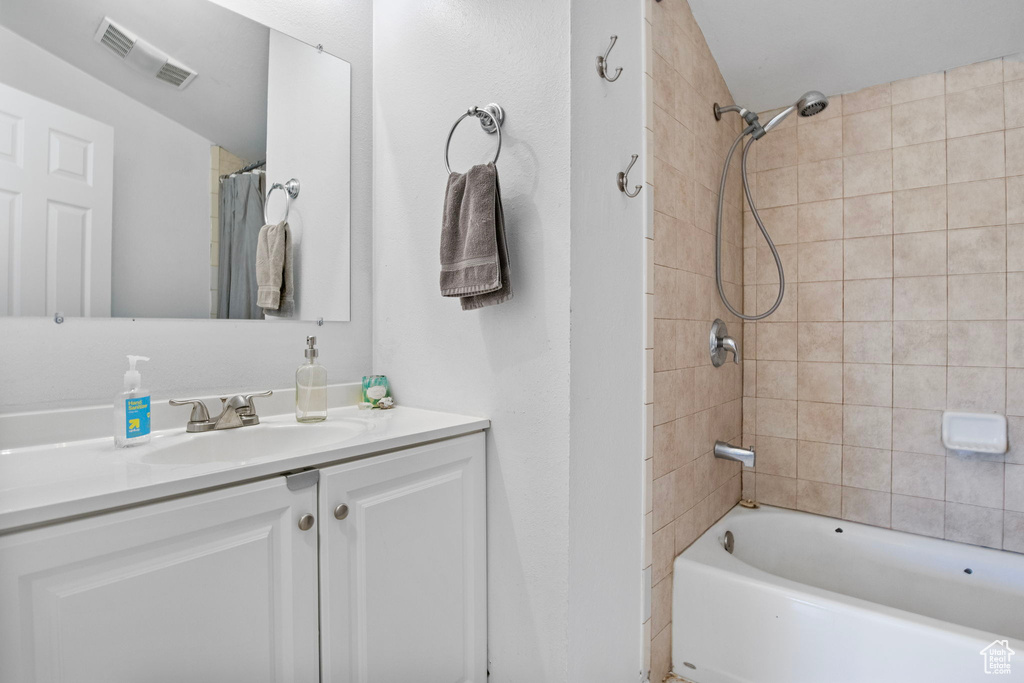 Bathroom featuring vanity and shower / bathtub combination with curtain