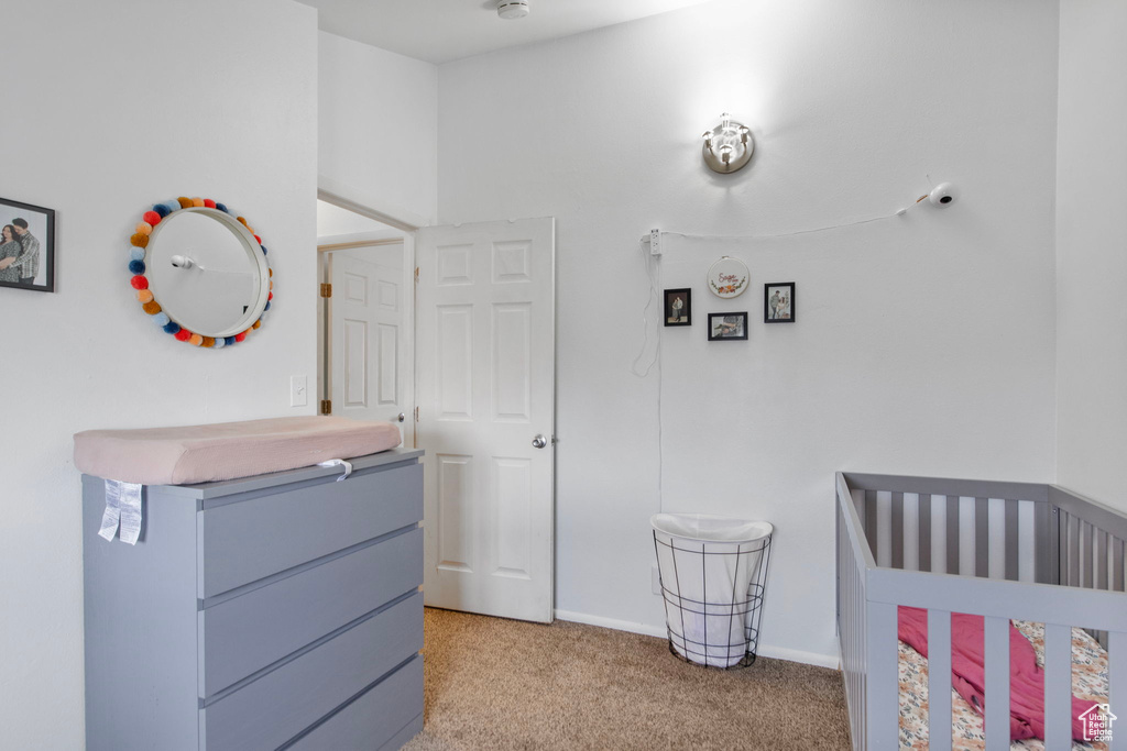 Bedroom with light colored carpet, a nursery area, and baseboards