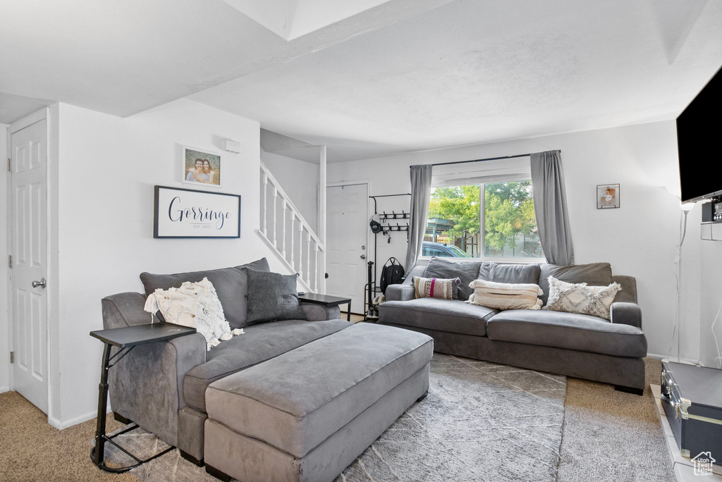 Carpeted living area with stairs