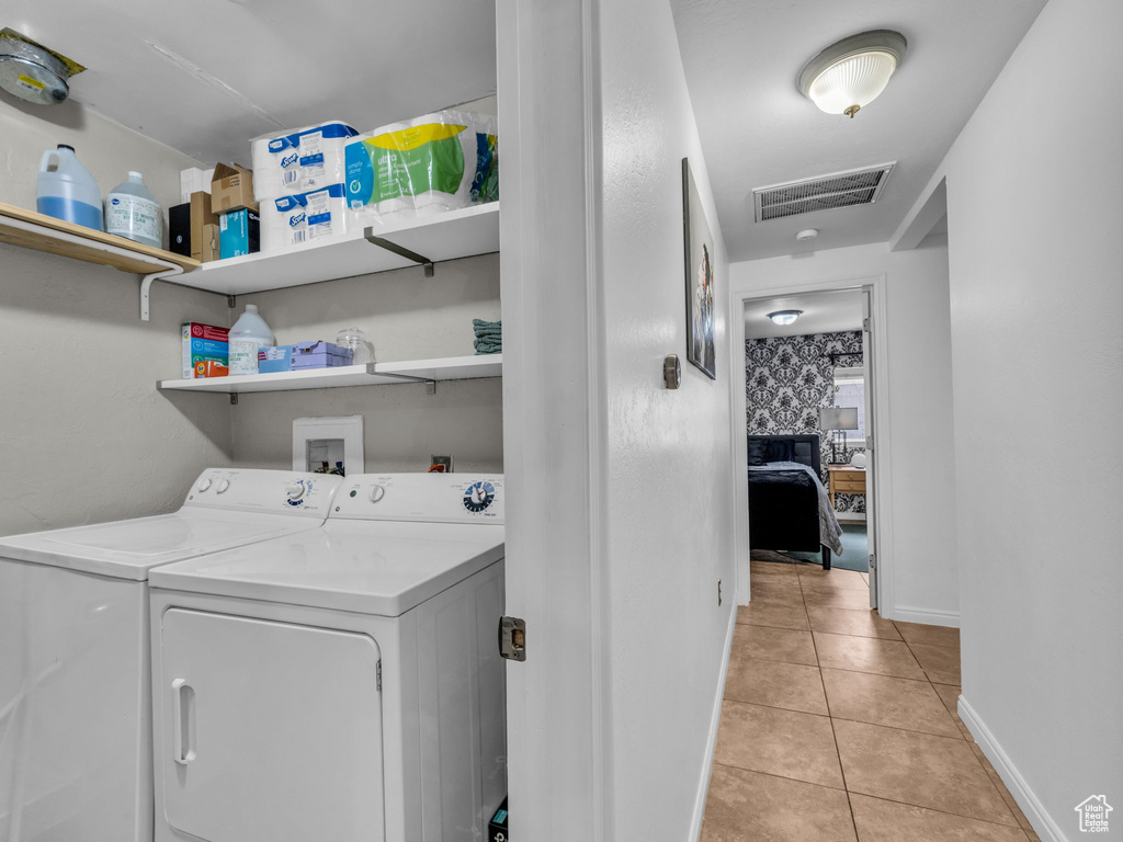 Laundry room with washer and dryer, light tile patterned flooring, and baseboards