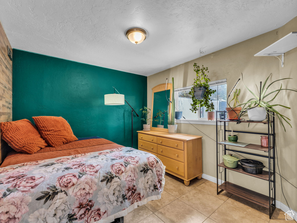 Bedroom featuring an accent wall, a textured ceiling, light tile patterned flooring, and baseboards