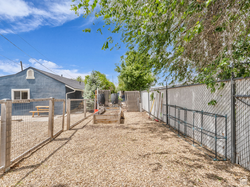 Fenced backyard featuring a vegetable garden and a gate