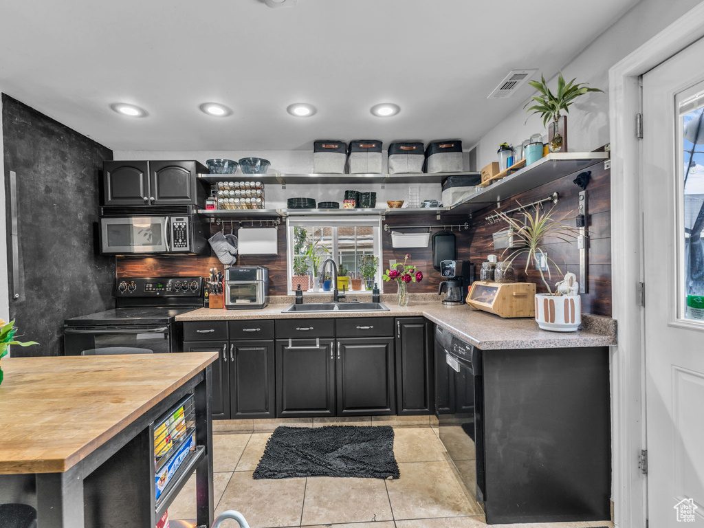 Kitchen with open shelves, black appliances, a sink, butcher block counters, and tasteful backsplash