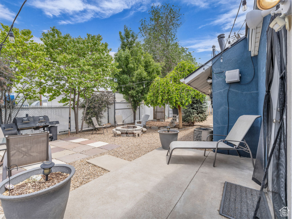Fenced backyard featuring a fire pit, a patio, cooling unit, and a grill