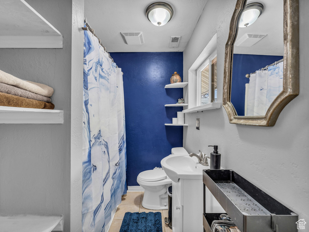 Bathroom featuring toilet, tile patterned floors, vanity, and a shower with shower curtain