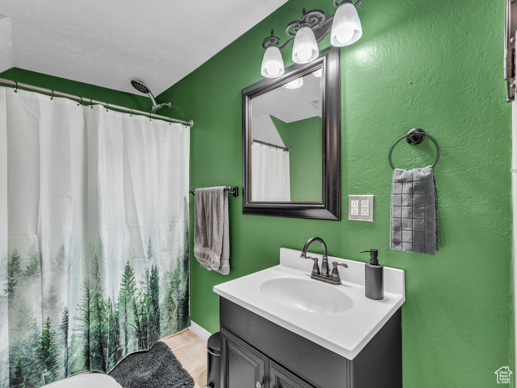 Bathroom featuring vanity, a textured wall, tile patterned flooring, and a shower with curtain