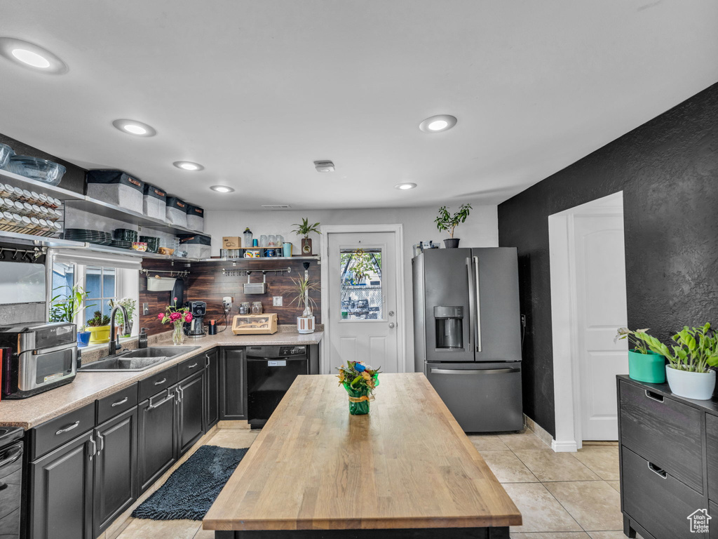 Kitchen with stainless steel fridge with ice dispenser, a sink, black dishwasher, wood counters, and recessed lighting