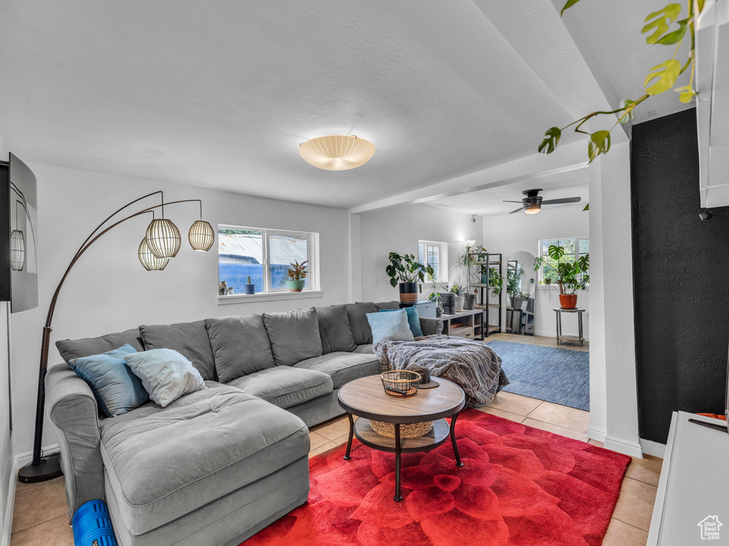 Living area featuring light tile patterned floors, a ceiling fan, and baseboards