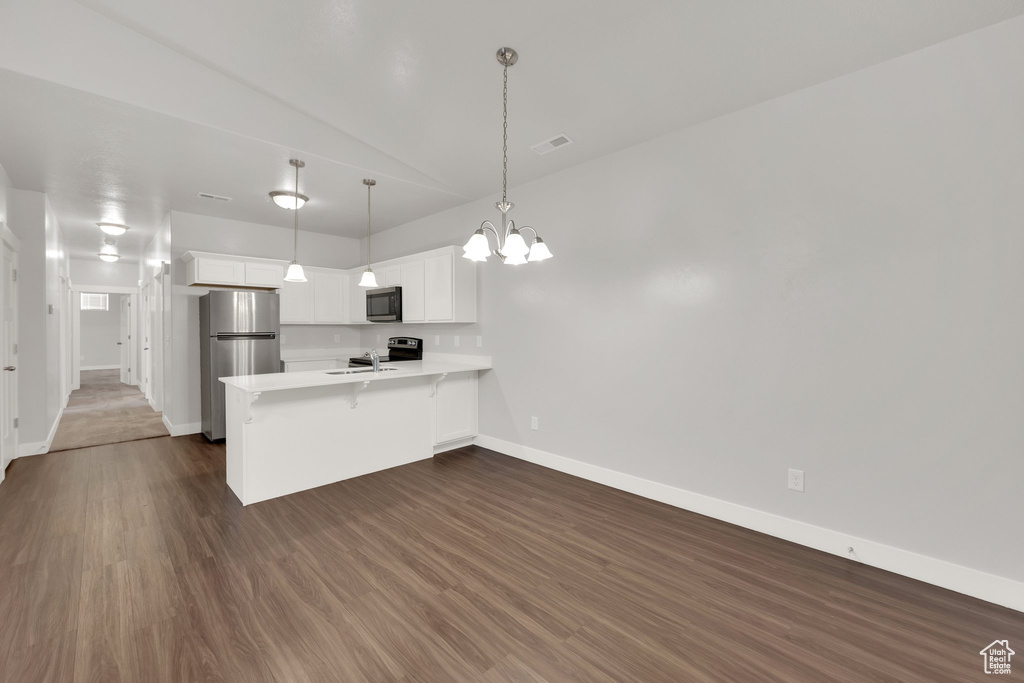 Kitchen featuring stainless steel appliances, a peninsula, baseboards, a chandelier, and light countertops