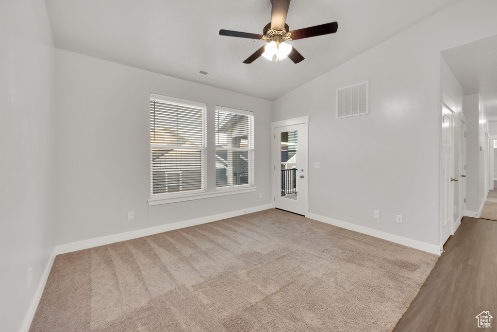 Spare room with vaulted ceiling, a ceiling fan, and baseboards