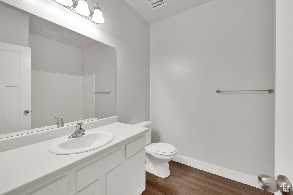 Bathroom featuring toilet, wood finished floors, vanity, and baseboards