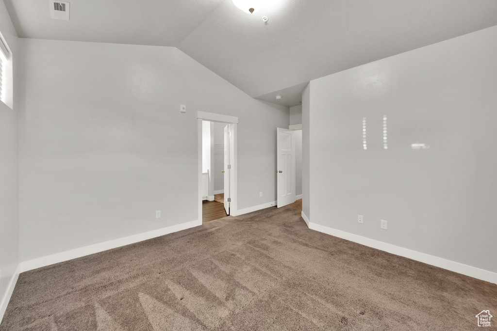 Unfurnished bedroom with lofted ceiling, carpet flooring, baseboards, and connected bathroom