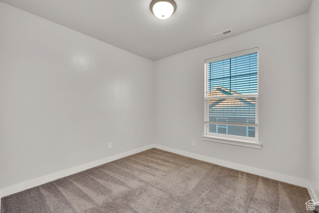 Carpeted spare room featuring baseboards