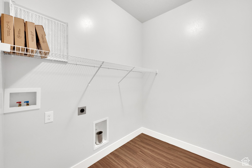Laundry area featuring hookup for a washing machine, electric dryer hookup, dark wood-style flooring, and baseboards