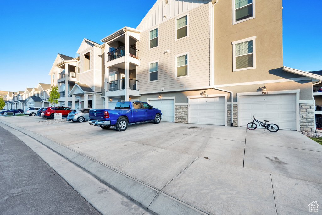 View of property with a garage, a residential view, and driveway