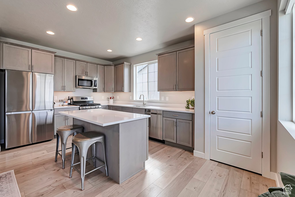 Kitchen with stainless steel appliances, a sink, a kitchen breakfast bar, a kitchen island, and recessed lighting