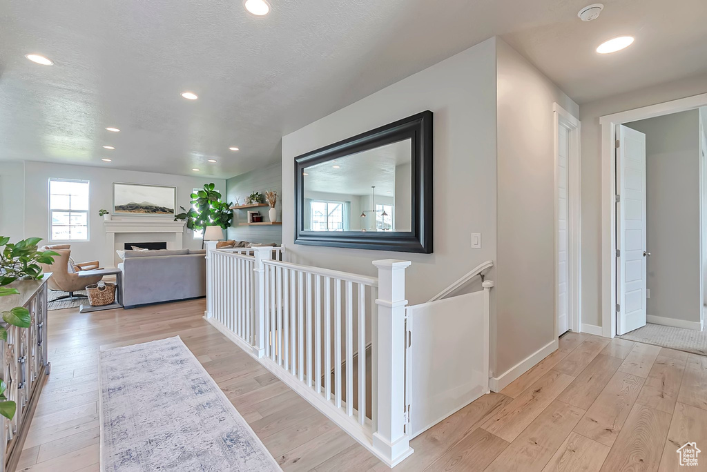 Hallway featuring wood-type flooring, baseboards, recessed lighting, and an upstairs landing