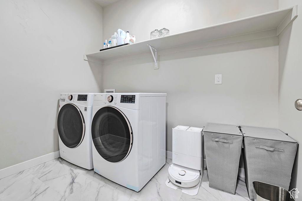 Washroom featuring independent washer and dryer, light marble finish floors, and baseboards