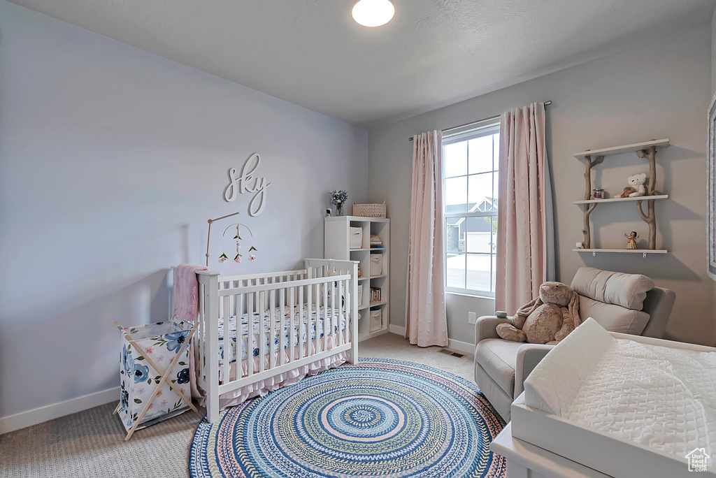 Carpeted bedroom with baseboards and a nursery area