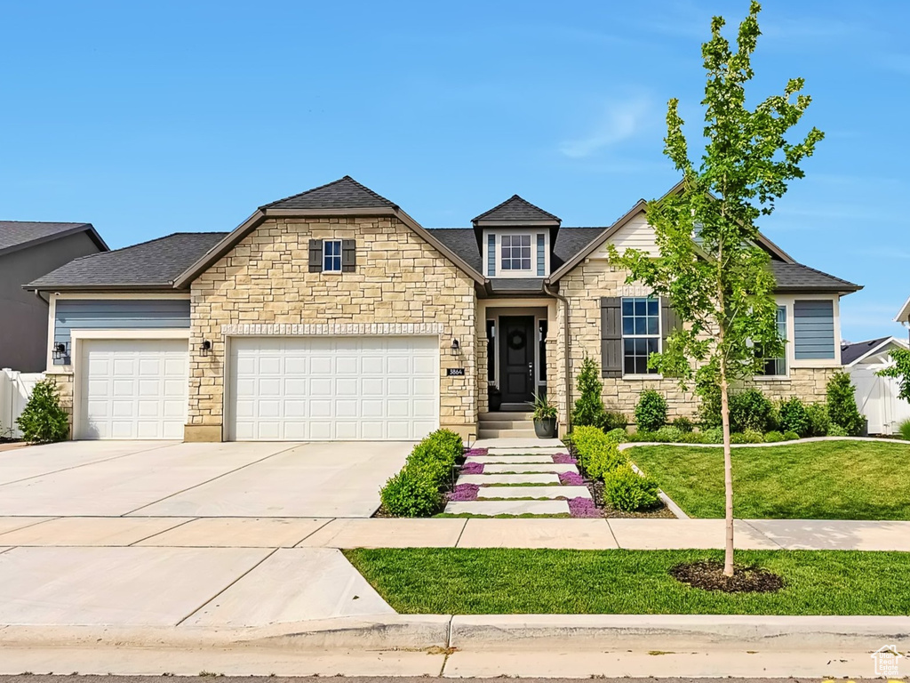 View of front of home with concrete driveway, an attached garage, and stone siding