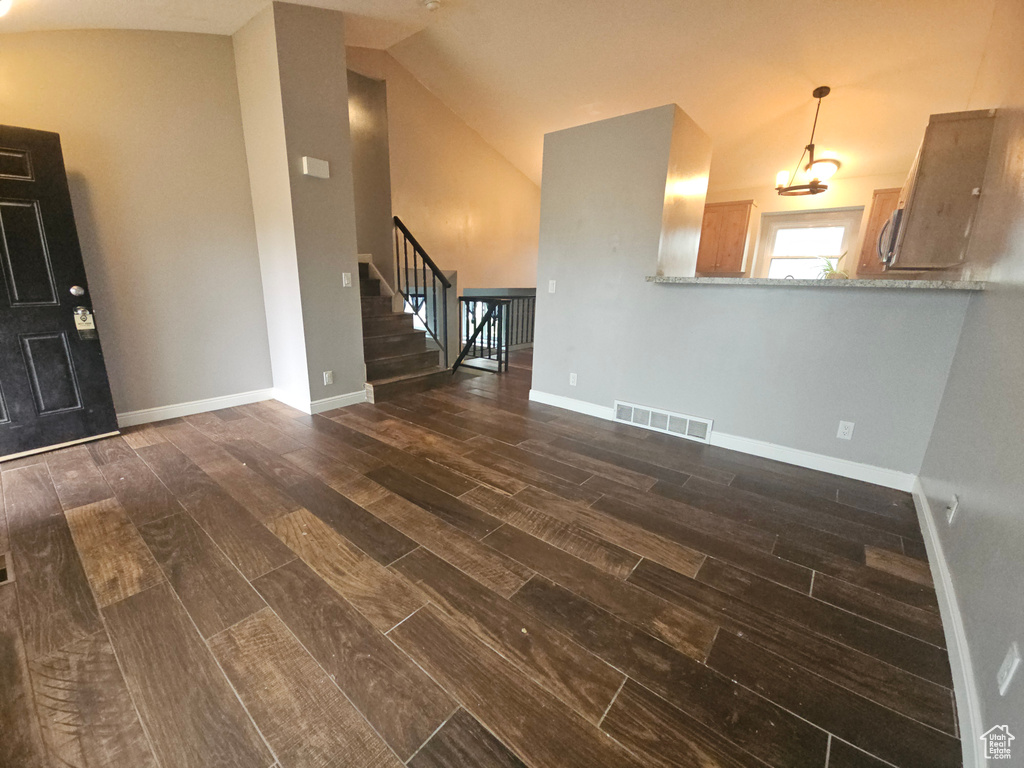 Unfurnished living room featuring wood finish floors, lofted ceiling, stairway, and baseboards