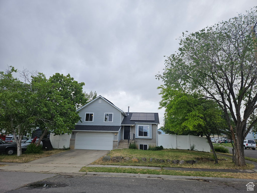 View of front of house with roof mounted solar panels, driveway, and an attached garage