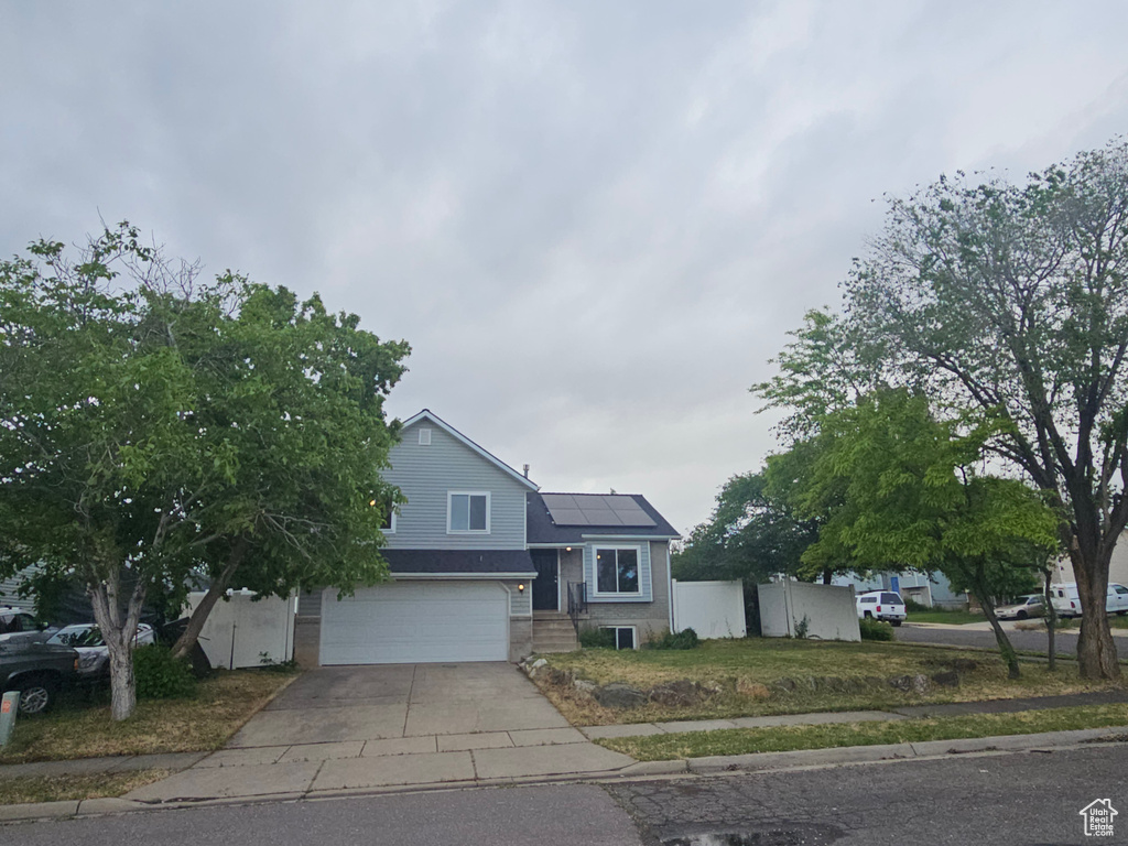 View of front of home featuring roof mounted solar panels, driveway, and an attached garage