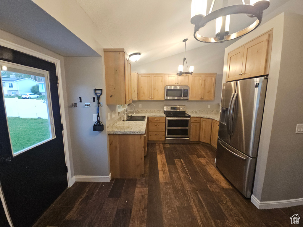 Kitchen featuring appliances with stainless steel finishes, a sink, light brown cabinets, dark wood finished floors, and vaulted ceiling