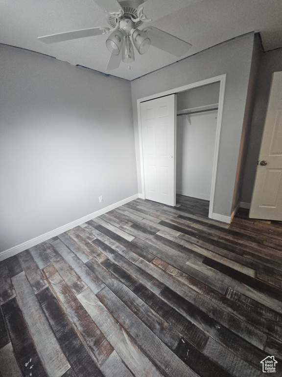 Unfurnished bedroom with dark wood finished floors, baseboards, a closet, and ceiling fan