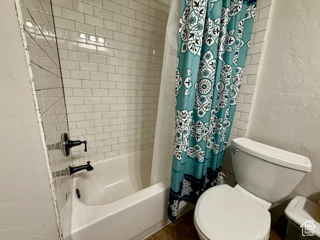 Bathroom featuring toilet and shower / bath combination with curtain