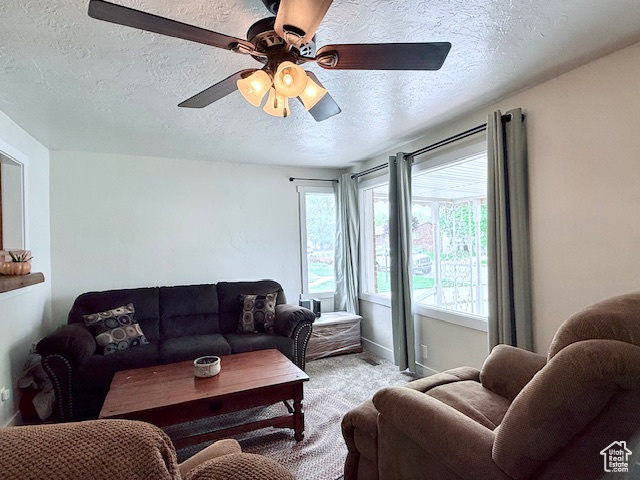 Living area featuring a textured ceiling, light colored carpet, and ceiling fan