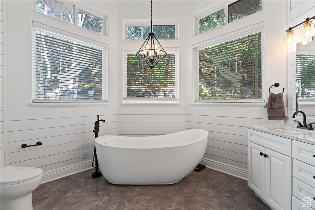 Bathroom with a chandelier, vanity, a freestanding bath, and toilet