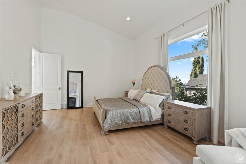 Bedroom with light wood-style floors and high vaulted ceiling