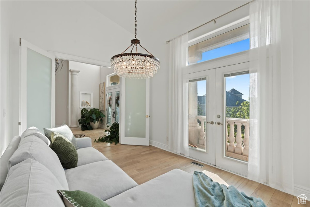 Living area with french doors, a chandelier, wood finished floors, and baseboards