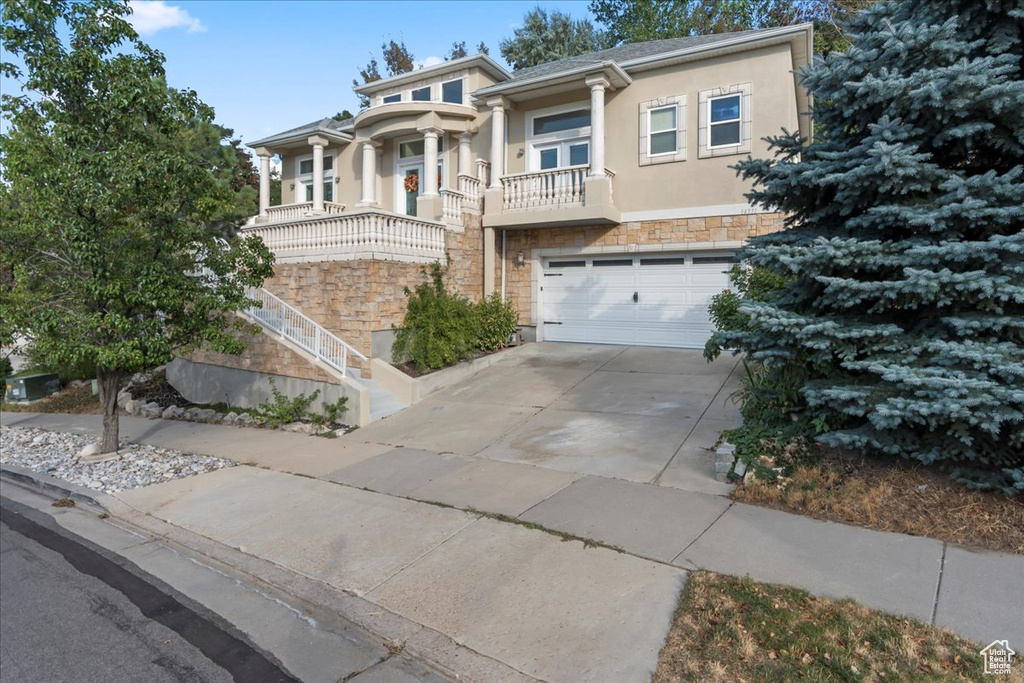 View of front of property with stone siding, stucco siding, driveway, and an attached garage