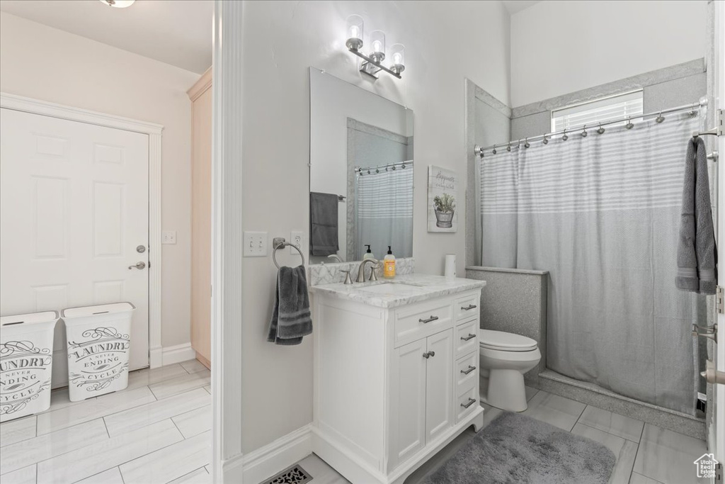 Bathroom featuring vanity, tile patterned flooring, a shower with curtain, toilet, and baseboards