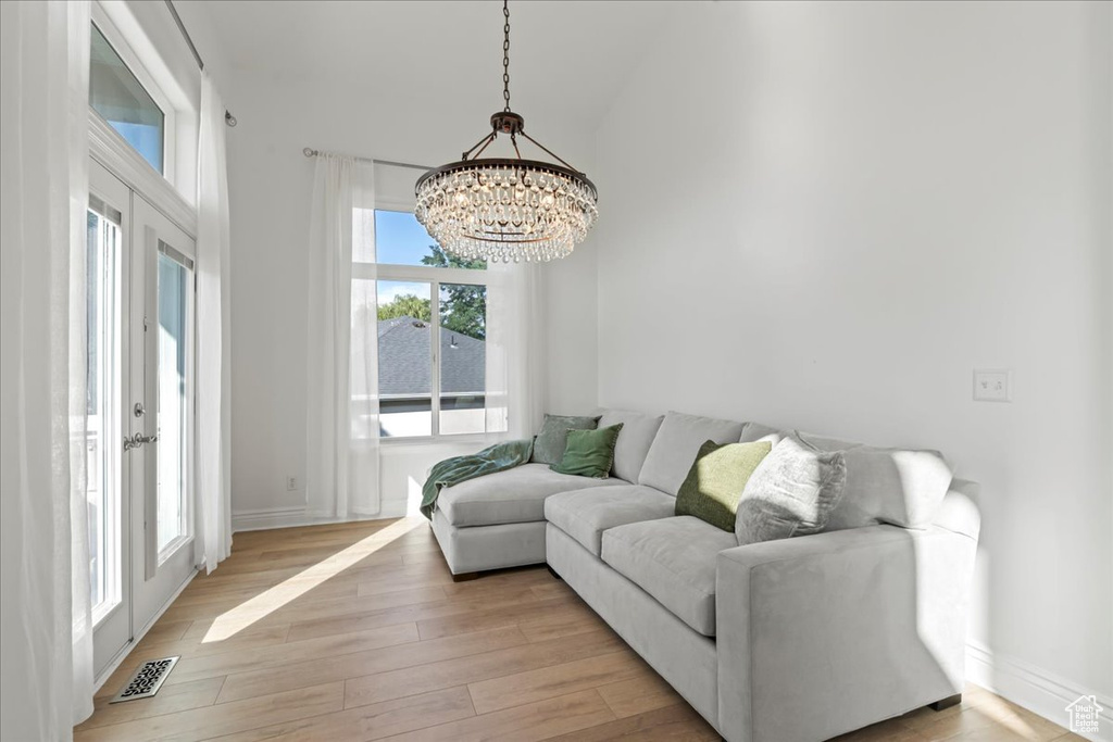 Living area with a chandelier, light wood-type flooring, and baseboards