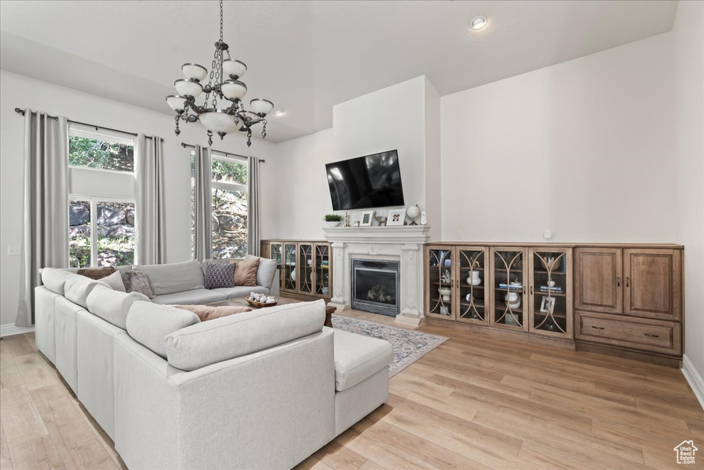 Living room featuring a chandelier, light wood-style floors, a glass covered fireplace, and recessed lighting